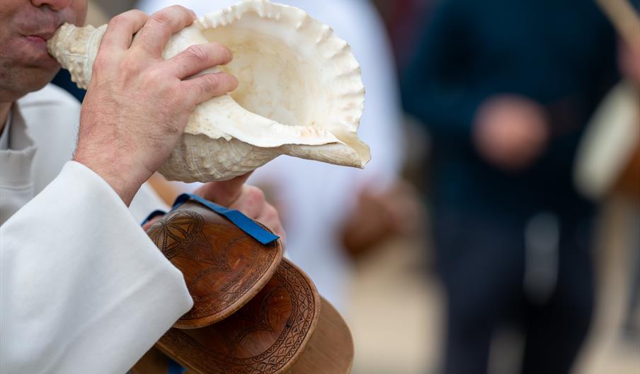Un hombre hace sonar una caracola de mar en la tradicional brulada de corn.