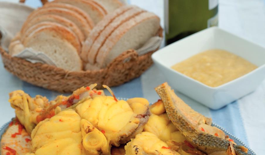 Bullit de peix, plato tradicional de la gastronomía ibicenca elaborado con pescado fresco, patatas y alioli, servido junto a pan y aceite de oliva.