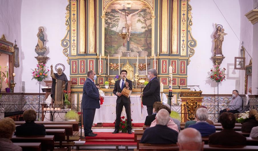 Tres hombres tocan diversos instrumentos durante los Caramelles de Pasqua en una iglesia.