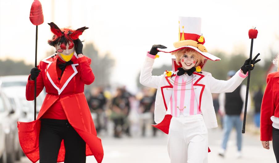 Dos personas disfrazada durante el Carnaval de Ibiza, una con indumentaria roja y otra con indumentaria roja, en lo que parece un disfraz de circo.