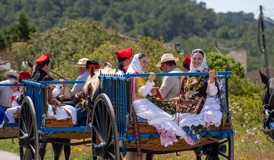 Varios hombres y mujeres, ataviados con el traje tradicional payés, pasean en carro de madera en las Festes de Sant Francesc de s'Estany.