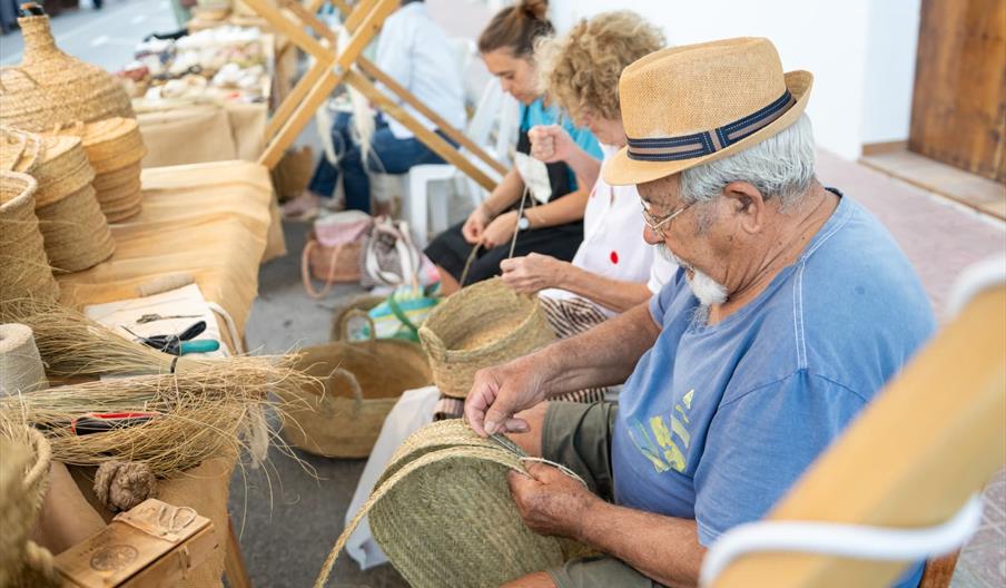 En la Festes de Sant Rafel, hombres y mujeres artesanos hacen canastos de mimbre.