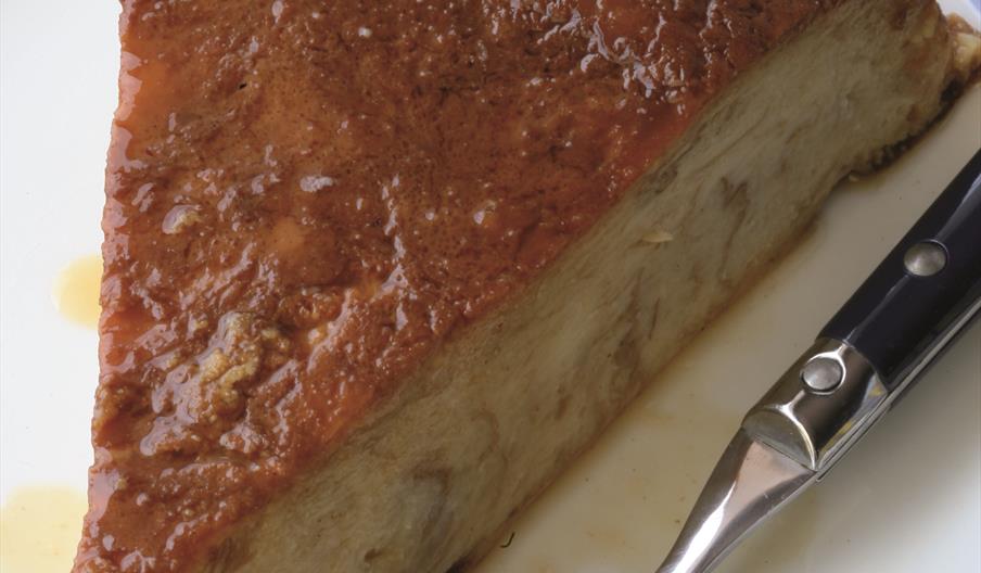 Primer plano de una porción de greixonera, el tradicional postre ibicenco elaborado con ensaimadas y huevo, de textura similar a un pudin y superficie