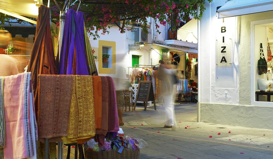Tenderete de una tienda en el barrio histórico de La Marina, en la ciudad de Eivissa, al anochecer. Al fondo se ven más tenderetes y el escaparate de