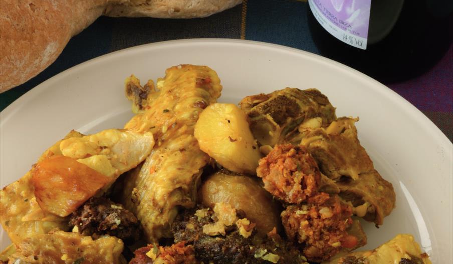 Sofrit pagès, plato tradicional de la gastronomía ibicenca elaborado con carnes, embutidos locales y patatas, una receta emblemática de las celebracio