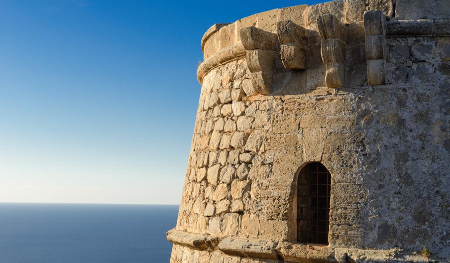 Detalle de la Torre des Savinar, antigua torre de vigilancia costera construida en piedra sobre el mar Mediterráneo en la costa de Ibiza.