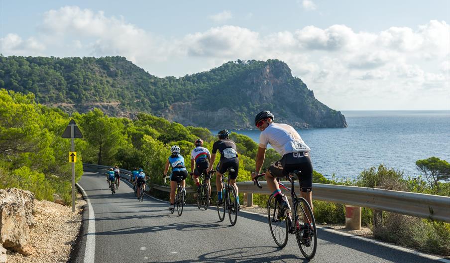 Varios corredores en carretera durante la Vuelta Cicloturista a Ibiza Campagnolo, con el Mediterráneo de fondo.