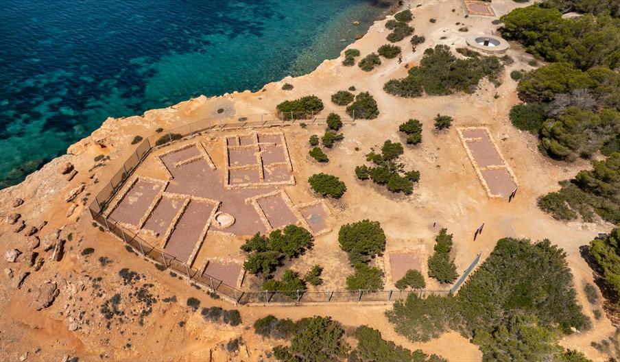 Se ve el asentamiento fenicio o poblado fenicio de Sa Caleta desde el aire, con los muros de las casas bien diferenciados. El mar Mediterráneo está ju