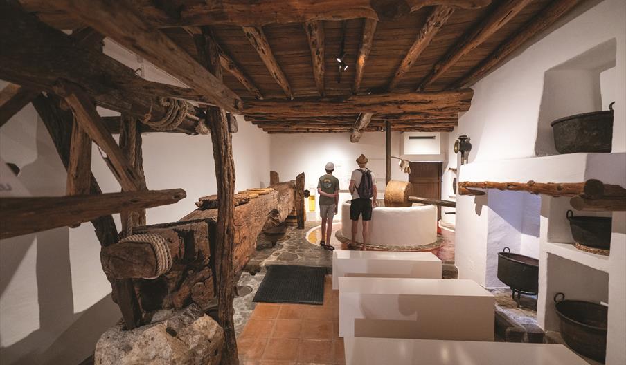 Vista del interior de Can Ros, Museo Etnográfico de Ibiza, donde puede verse a una pareja de visitantes viendo los diferentes utensilios y herramienta