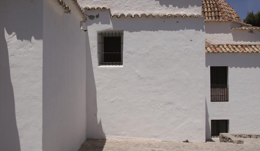 Detalle de la Iglesia de Santo Domingo en Dalt Vila, con fachadas encaladas, cúpulas de teja tradicional y pavimento de piedra bajo un cielo despejado