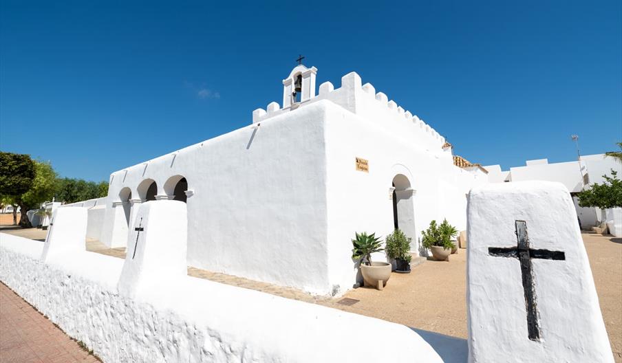 La iglesia es blanca, al estilo ibicenco. Tiene tres arcos en su fachada iquierda y, arriba de la puerta de entrada, en la fachada principal, aparece