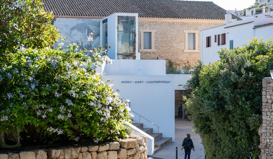 Exterior del Museo de Arte Contemporáneo de Ibiza (MACE) en Dalt Vila, rodeado de vegetación mediterránea y arquitectura tradicional ibicenca en un en