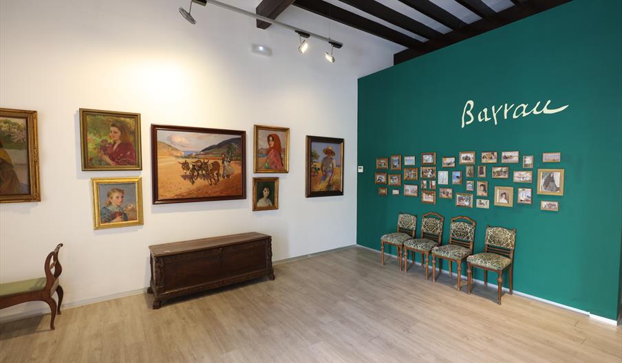 Interior de la Sala Barrau con numerosas obras de arte. También hay un baúl y sillas.