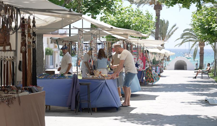 Puestos de artesanía y productos locales en el Mercadillo Hippy del Passeig de S’Alamera, junto al paseo marítimo y las palmeras de Santa Eulària des
